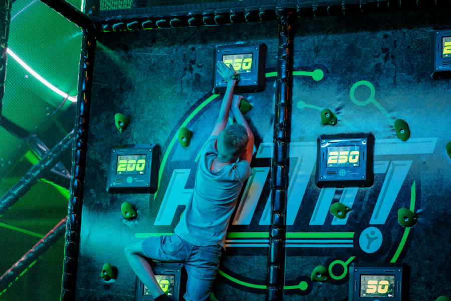 Een kind klimt op de klimmuur om de hoogste score te halen in de Hit-It-Arena