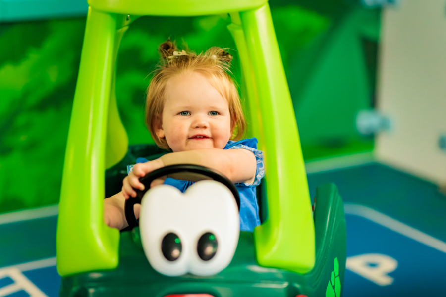 Een peuter zit in een loopauto